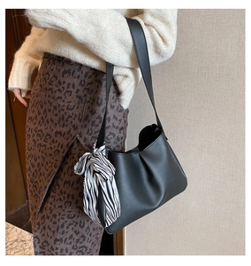 Detail of matte black leather shoulder bag with zebra print scarf on wide strap