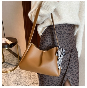Detail of caramel leather shoulder bag with decorative zebra print silk scarf on handle