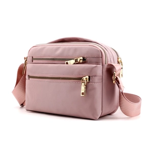 Water-resistant light pink crossbody bag with three zipper compartments and gold hardware