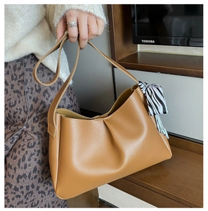 Detail of camel PU leather underarm bag with zebra print scarf on a pleated handle