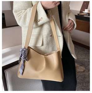 Detail of elegant beige shoulder bag with stylish black and white striped scarf decoration