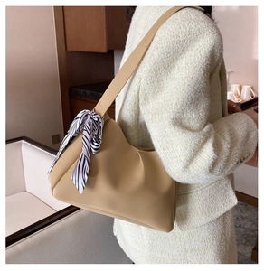Detail of light brown faux leather shoulder bag featuring side pleats and zebra print scarf