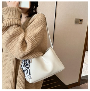 Detail of minimalist beige PU leather shoulder bag with decorative zebra print silk scarf