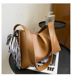 Detail of brown leather tote bag with elegant pleated design and zebra print silk scarf