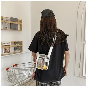 Minimalist clear PVC crossbody bag with white trim shown in a trendy supermarket setting