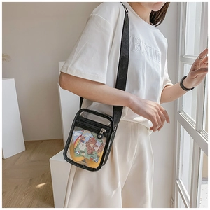 Detailed view of a transparent PVC crossbody bag with a black zipper and strap worn by a model
