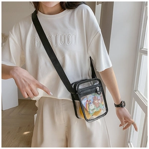 Close-up of clear PVC crossbody bag with black zipper and adjustable strap on a model