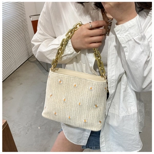 Detailansicht der gewebten Strohtasche mit gelber Gänseblümchen-Stickerei und goldener Kette