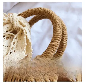 Detailed macro view of woven straw handbag handle featuring a large white lace bow