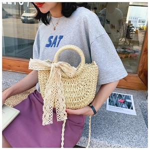 Detail of beige woven straw handbag with intricate lace bow and stylish circular handle