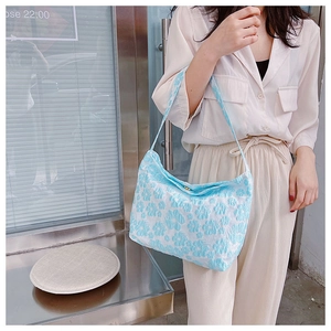 Détail du tissu jacquard à fleurs bleues avec texture en relief sur un sac cabas
