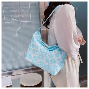 Vue latérale d'un sac à bandoulière bleu clair avec motifs floraux en relief sur un mannequin