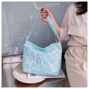 Détail du sac en toile à fleurs avec texture gaufrée et fermeture magnétique dorée