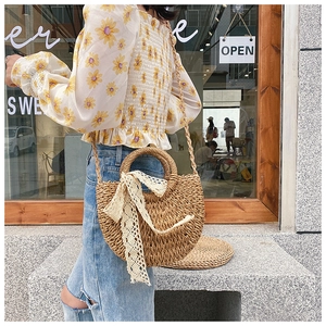 Detail of hand-woven straw crossbody bag featuring delicate white lace bow decor