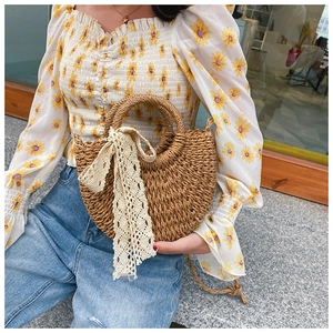 Detail of handmade half-moon straw bag with elegant lace drawstring and round top handle