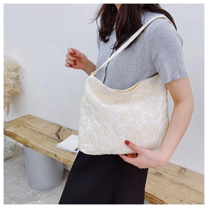 Détail de la texture jacquard florale 3D sur un sac à bandoulière en toile blanc cassé