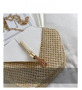 Detail of woven straw shoulder bag featuring a white leather flap and gold chain strap