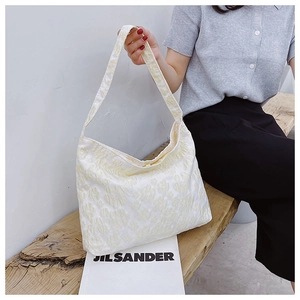 Gros plan détaillé du tissu jacquard floral 3D blanc ivoire sur un sac Hobo chic