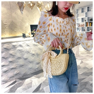 Detail view of handmade straw handbag with white lace bow decoration and semi-circular design