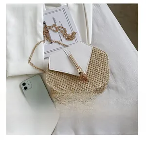 Detail view of woven straw and white PU leather hexagonal bag with gold tassel