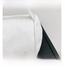 Detail showing white floral embossed texture and zipper on minimalist shoulder bag