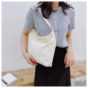Détail du sac bandoulière jacquard crème avec textures florales 3D et bandoulière fine