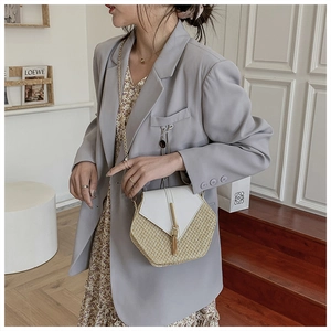 Detail shot of woven PU leather bag with gold tassel and elegant chain strap on a model