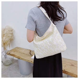 Gros plan détaillé du sac cabas en toile crème avec motifs floraux en relief