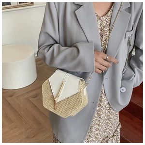 Chic woven straw crossbody bag with white leather flap and gold chain on a female model
