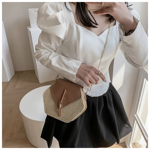 Detail of woven straw hexagonal crossbody bag with brown leather flap and gold tassel