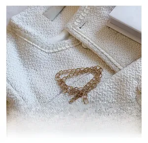 Détail du tissu en tweed blanc avec bordure en chaîne dorée et étiquette de marque