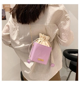 Détail du sac seau lavande avec surpiqûres ondulées et bandoulière chaîne dorée