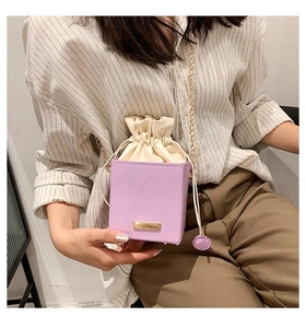 Détail du petit sac violet carré à texture ondulée et bandoulière en chaîne dorée