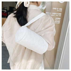 Detail of white jacquard cylinder bag showing textured fabric and wide shoulder strap