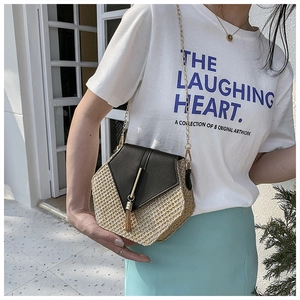 Detail of hexagonal woven straw bag with black leather flap and gold chain strap