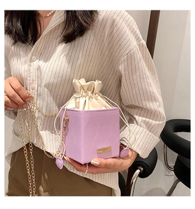 Détail du sac seau violet clair avec cordon, chaîne dorée et texture ondulée élégante