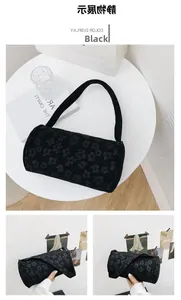 Detail view of a black cylindrical bag featuring embossed floral patterns and a sleek strap