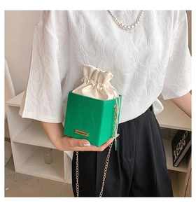 Détail du mini sac seau vert avec texture ondulée et chaîne dorée à la main