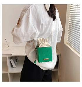 Détail du petit sac seau vert clair texturé avec bandoulière en chaîne dorée