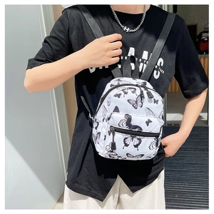 Close-up of a white mini butterfly print backpack with black nylon straps on a model