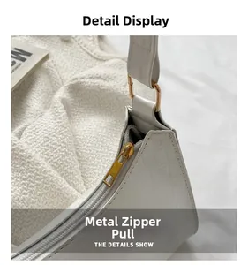 Close-up of white crocodile pattern PU leather with golden hardware zipper and D-ring detail