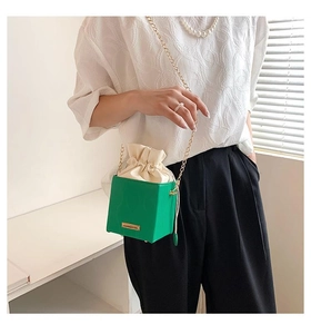 Détail du sac bandoulière boîte vert avec perles et chaîne dorée sur un mannequin