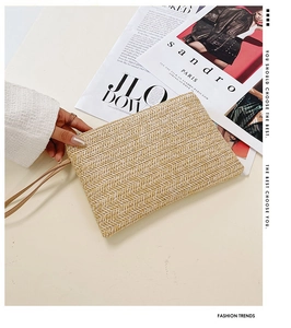 Detail of herringbone weave texture and leather wrist strap on a natural straw clutch bag