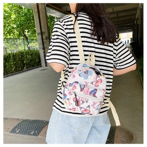 Detail shot of a small canvas backpack with colorful butterfly print on a white background