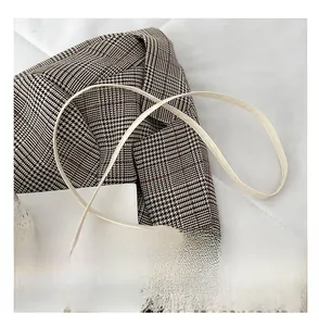 Dettaglio della tracolla comfort di una borsa rotonda in tessuto colore beige