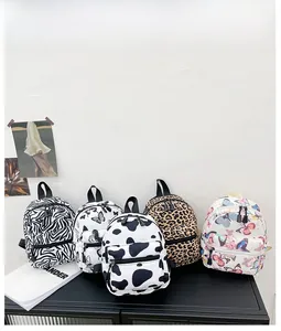 Detailed flat lay of five mini canvas backpacks with zebra, cow, leopard and butterfly prints