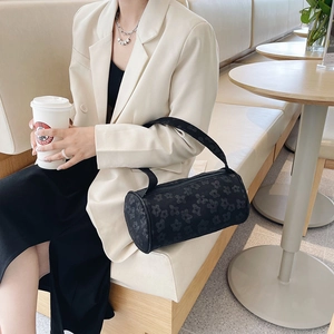 Fashionable black cylindrical underarm bag with floral texture and crossbody strap