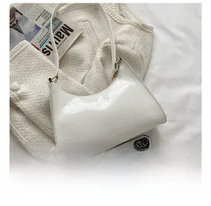 Detailed view of white crocodile pattern shoulder bag compared to a smartphone for size