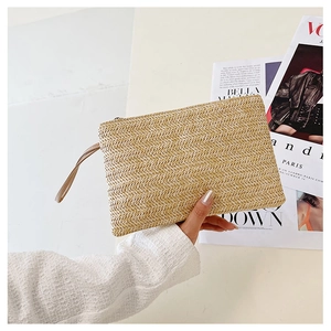 Detailed herringbone weave pattern on beige straw clutch with brown leather strap
