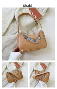 Detail of khaki baguette bag with silver chain and blue butterfly charms on soft fabric
